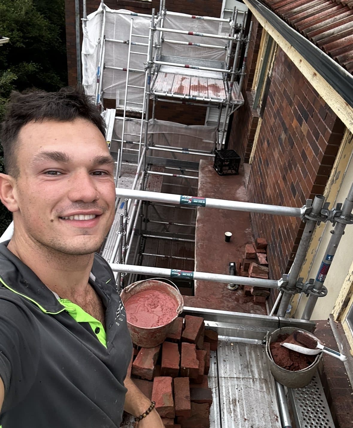 Luca smiling on a scaffold at a building site