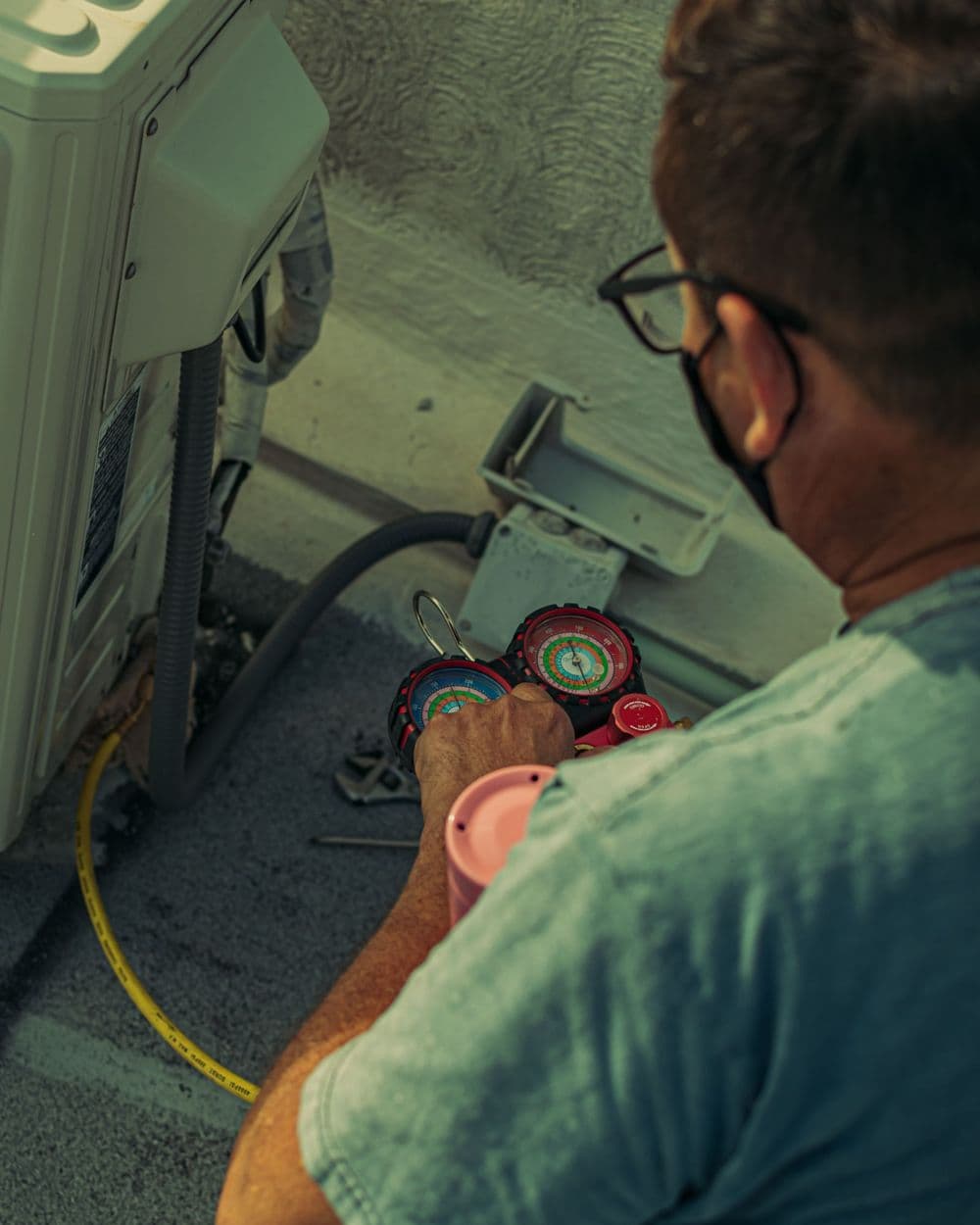 HVAC technician checking an outdoor air conditioning unit with gauges